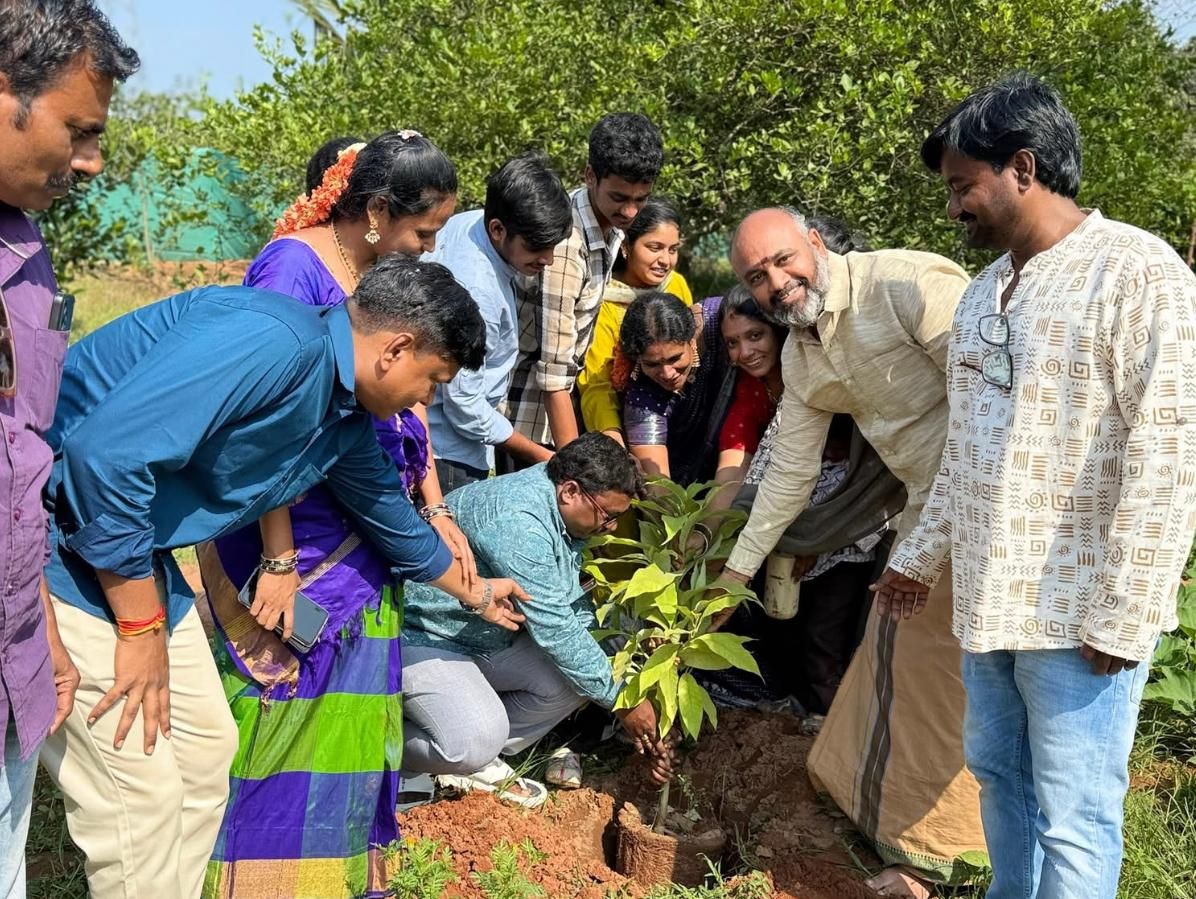 A group gathered around a sapling being planted
